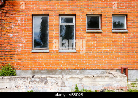 Rosso vecchio muro di mattoni con alcune finestre. Architeture dettaglio sullo sfondo Foto Stock