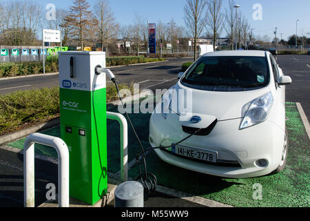 Maynooth, nella contea di Kildare, Irlanda. 20 FEB 2018: veicoli elettrici Nissan Ecar nota che viene addebitata alla ESB punto di carica. Carica batteria auto diventando più e più accessibile con un crescente numero di stazioni di carica ora facilmente trovato sulla strada, centri commerciali e parcheggi. Foto Stock