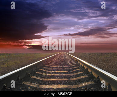 Lugubre paesaggio con rotaie di andare lontano nel lontano tramonto Foto Stock