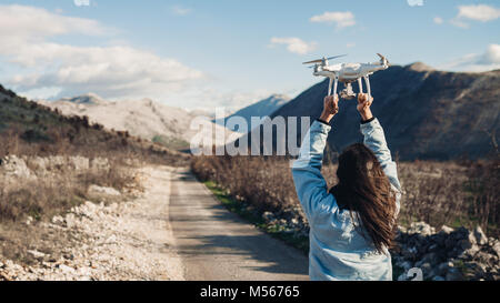 Giovane donna videografo la cattura di aeromobile che vola con la fotocamera.Controllare lo sbarco di fuco.regista femmina in natura utilizzando quad copter aeromobile a ca Foto Stock