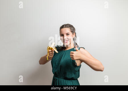 Ritratto di un sano giovane ragazza europea holding banana giallo isolato su sfondo bianco Foto Stock