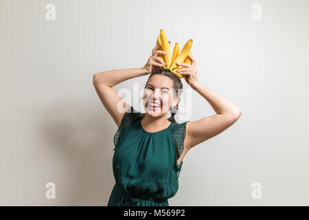 Ridere ragazza adolescente mette le banane su una testa Foto Stock