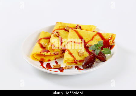 Frittelle con le noci e le date e rabboccato con sciroppo di data sulla piastra bianca Foto Stock