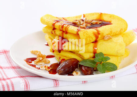 Frittelle con le noci e le date e rabboccato con sciroppo di data sulla piastra bianca Foto Stock