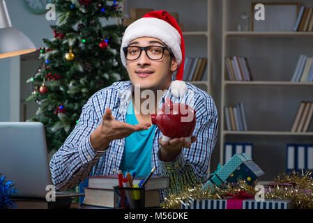 Giovane uomo che lavora a casa il giorno di Natale Foto Stock