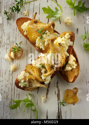 Giallo funghi Oyster saltate in burro e serviti con confuse uovo sulla pasta acida pane tostato con Wild Rocket Foto Stock