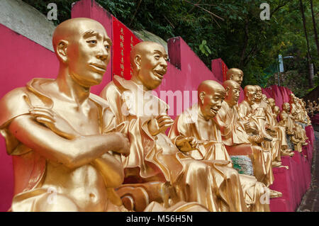 Golden Statue di Buddha lungo la scalinata per il Monastero dei Diecimila Buddha e paesaggio con alberi verdi in background in Hong Kong. Ho Foto Stock