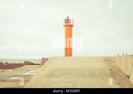 Faro arancione alla fine del molo. Mar baltico. Foto Stock