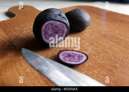 Viola a fette di patate su un tagliere Foto Stock