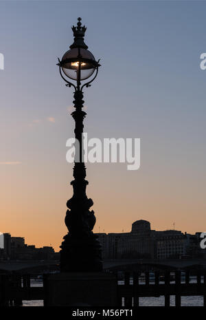 Strada elegante lampada luce ed edifici stagliano contro un cielo chiaro al tramonto, lampada assomiglia a una faccia con le caratteristiche facciali come gli occhi Foto Stock