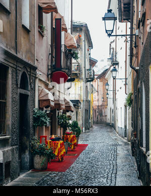 In ciottoli di caratteristico vicoletto in Aosta, Italia con un invitante tappeto rosso entrata al ristorante italiano a sinistra Foto Stock