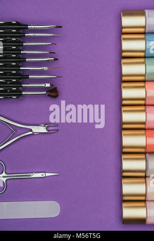 Vista superiore di strumenti per manicure e smalti per unghie isolati su viola Foto Stock