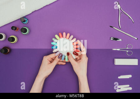 Immagine ritagliata della donna scegliendo il colore per unghie manicure con tavolozza Foto Stock