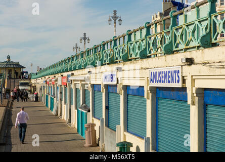 La gente camminare lungo la passeggiata sul lungomare di Brighton, East Sussex, Inghilterra. Negozi e caffetterie chiuso. Foto Stock