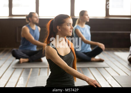 Attraente yogi donna e un gruppo di persone in Matsyendrasana Foto Stock