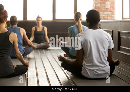 Un gruppo di giovani sportivi in seduta Sukhasana, vista posteriore Foto Stock