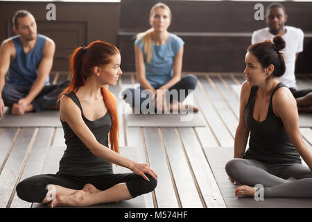 Due giovani belle montare le donne parlando al gruppo di formazione yoga Foto Stock