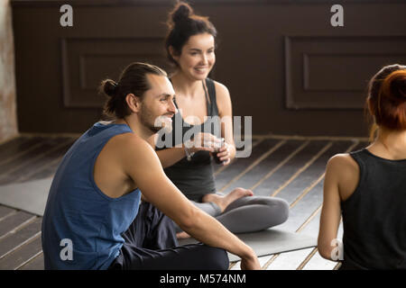 Memore sorridente yogi uomo seduto sul tappetino in un training di gruppo Foto Stock