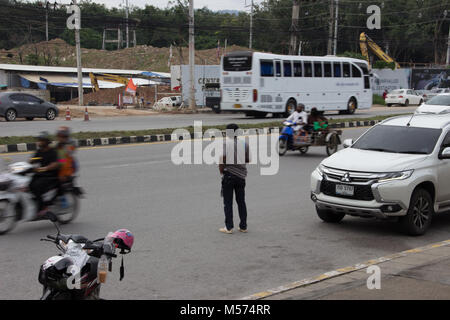 L uomo si trova in una strada trafficata a guardare il traffico, persone sullo scooter fuori Festival centrale di Phuket Foto Stock