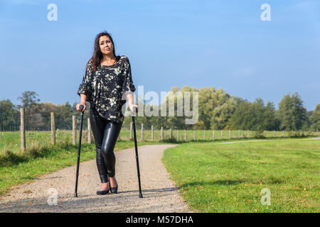 Donna disabile passeggiate sulle stampelle in natura Foto Stock