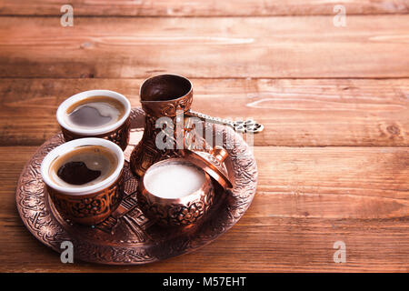 In bronzo antico brocca e tazza di caffè impostata con date in un vassoio isolato su uno sfondo bianco,caffè turco impostato su sfondo di legno.. Foto Stock