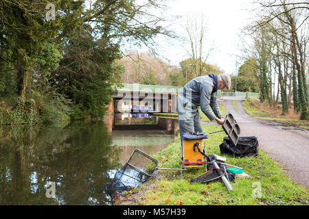 Lone pescatore mettere via il suo attacco isolato su alzaia dopo mattina la pesca nel canale UK. Pesca UK. Foto Stock