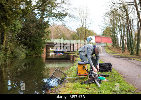 Lone pescatore mettere via il suo attacco isolato su alzaia dopo mattina la pesca nel canale UK. Pesca UK. Foto Stock