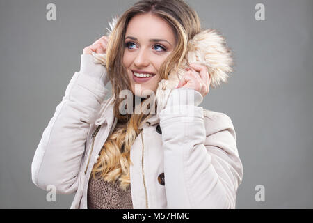 Bella timido Hipster ragazza in abbigliamento invernale,crema giacca con pelliccia, bella ragazza bionda - Stock immagine. Foto Stock