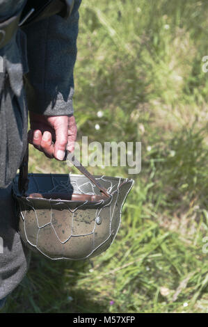 Mano umana tenendo un elmetto tedesco dalla seconda guerra mondiale Foto Stock