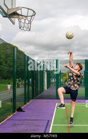 Ragazzo giovane di età compresa tra i 13 gioca a basket in Ballincollig Parco Regionale, County Cork, Irlanda con copia spazio. Foto Stock