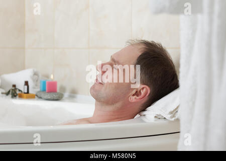 Uomo adulto avente una vasca da bagno con olio essenziale Foto Stock
