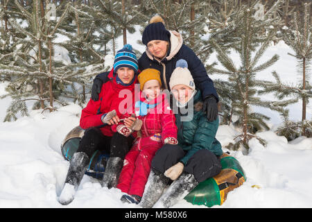 Ritratto di una madre con tre bambini aventi un periodo di riposo dopo lo sci su una vasca Foto Stock