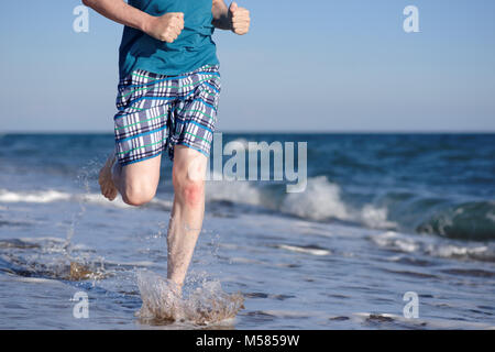 A piedi nudi uomo maturo durante il jogging sulla spiaggia Foto Stock