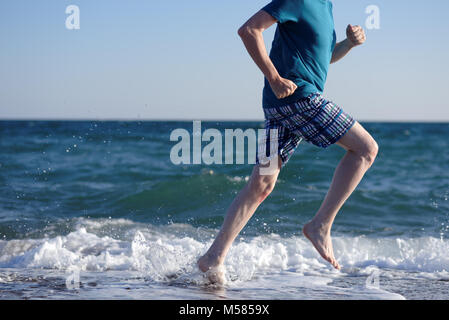 A piedi nudi uomo maturo durante il jogging sulla spiaggia Foto Stock