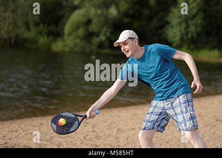 Uomo maturo giocare beach tennis su una spiaggia Foto Stock