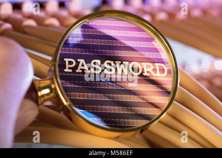 Immagine ritagliata di mano analizzando la password attraverso la lente di ingrandimento su cavi in sala server Foto Stock