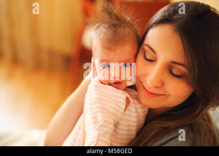 Giovane madre tenendo il suo bambino neonato. Mom lattante. La famiglia a casa. Close up Foto Stock