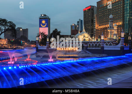 Kuala Lumpur in Malesia: Gennaio 25, 2018: edifici per uffici e Palazzo Sultano Abdul Samad Jamek moschea con fontana illuminata di notte sulle rive del Kl Foto Stock