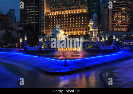 Kuala Lumpur in Malesia: Gennaio 25, 2018: edifici per uffici e Palazzo Sultano Abdul Samad Jamek moschea con fontana illuminata di notte sulle rive del Kl Foto Stock