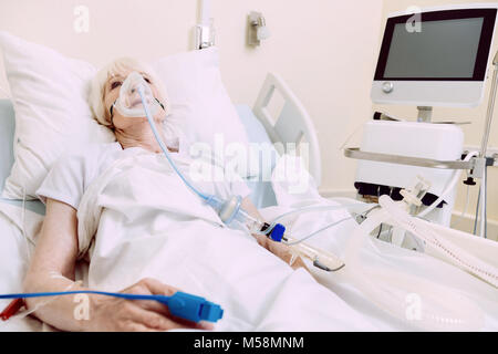 Donna con il supporto respiratorio che subisce il trattamento in ospedale Foto Stock
