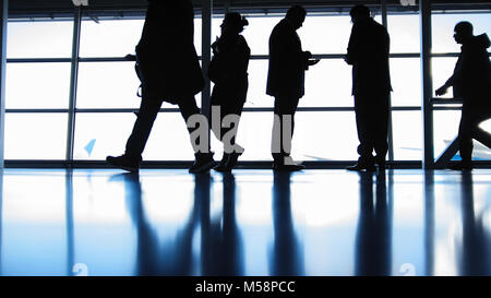 Seguire i passeggeri di salire a bordo con i bagagli nella parte anteriore del vetro in aeroporto, silhouette Foto Stock