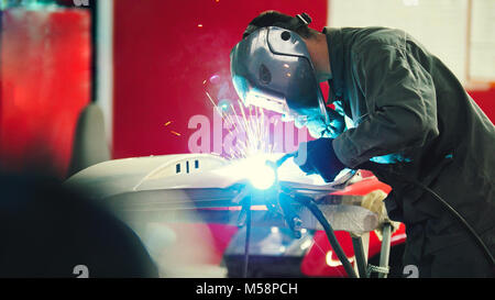 La saldatura industriale: il lavoratore nel casco dettagli della riparazione in auto auto service - blu botti Foto Stock