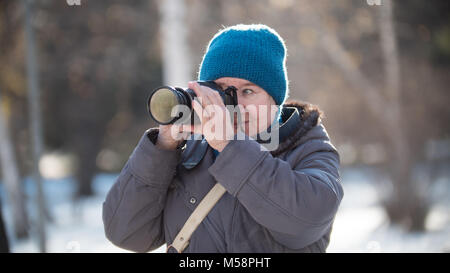 Senior donna con foto fotocamera in soleggiata giornata invernale, per esterno Foto Stock