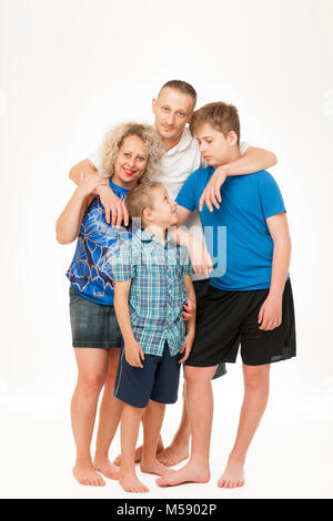 Corpo pieno di ritratti di una giovane famiglia permanente con il padre, madre e due ragazzi contro uno sfondo bianco. Foto Stock