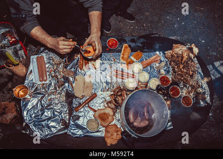 Una persona cucina grigliate di carne durante una festa in giardino Foto Stock