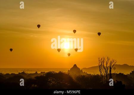 Mongolfiere volare sopra le pagode di Bagan e nebbiose pianure del sito archeologico durante il sunrise Foto Stock