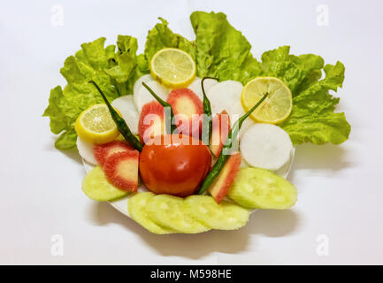 Insalata visualizzata su una piastra con pomodoro foglia di cavolo le carote affettate il cetriolo e limoni con peperoncino verde. Foto Stock