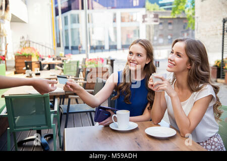 Le giovani donne di pagare per il caffè a street cafe Foto Stock