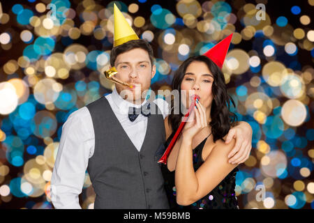 Coppia felice con party soffianti divertendosi Foto Stock