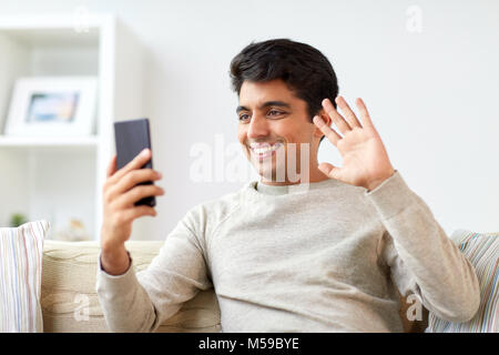 Uomo felice avente chiamata video sullo smartphone a casa Foto Stock